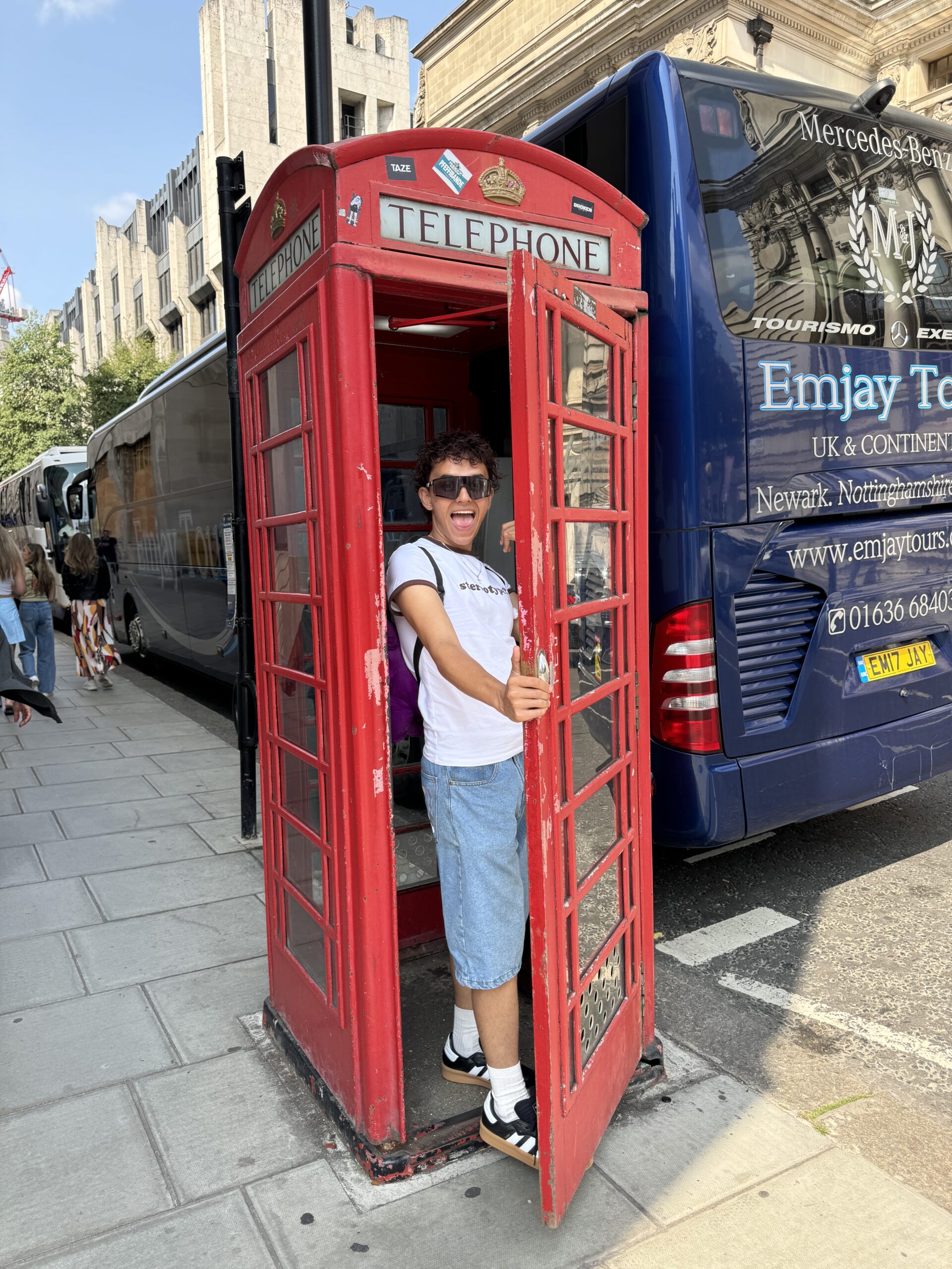 Sebas standing in a red phone box in London, enjoying the vibrant energy of the city as part of his creative journey.